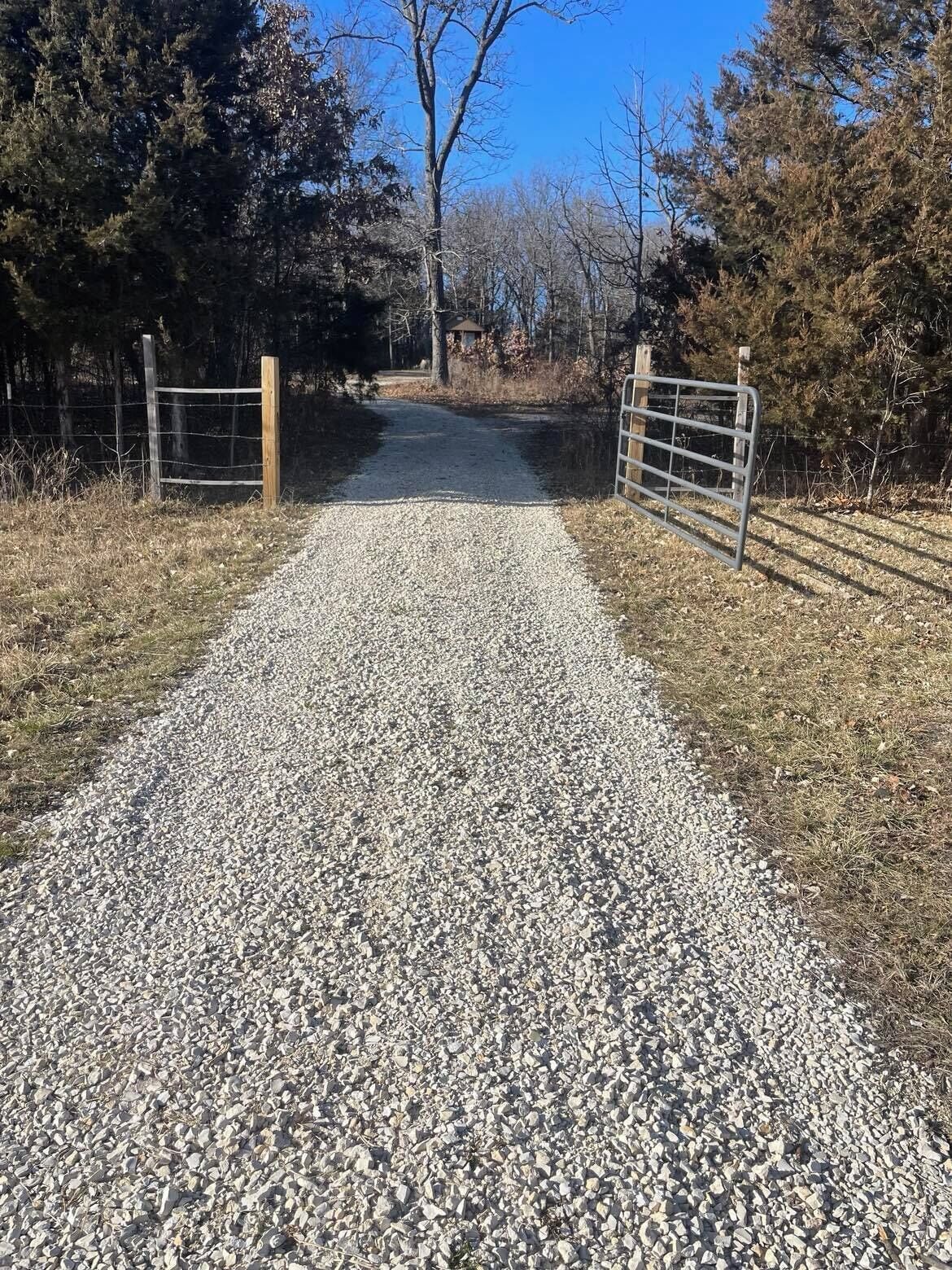 A gravel path leading to a gated area with wooden posts and metal gates.