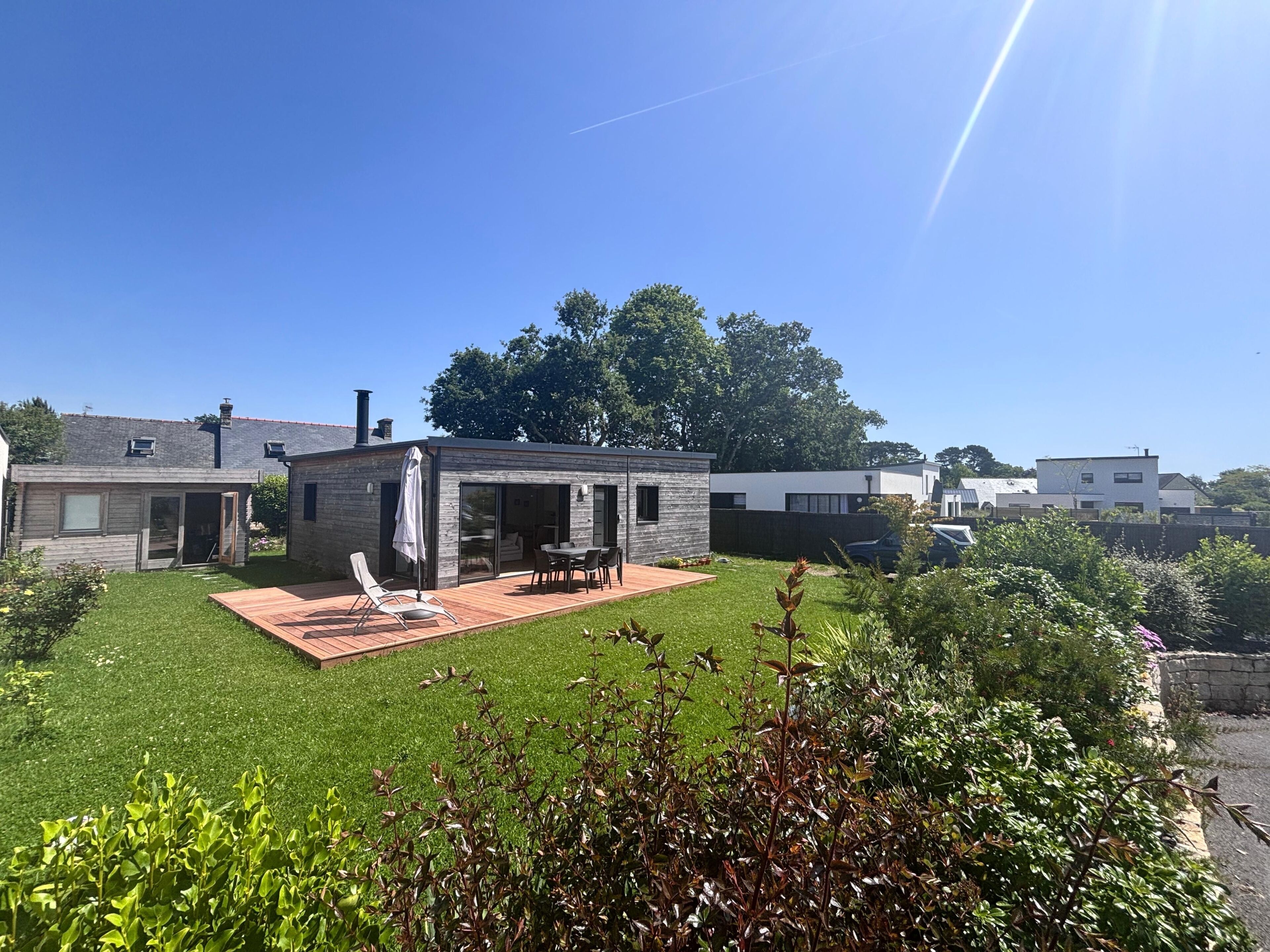 Et moderne hus med terrasse, græsplæne og udsigt til nabohuse.