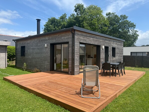 Ein modernes Haus mit einer Terrasse, einer Schiebetür und einem Schornstein.