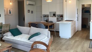 A modern living space with a sofa, dining table, and kitchen area.