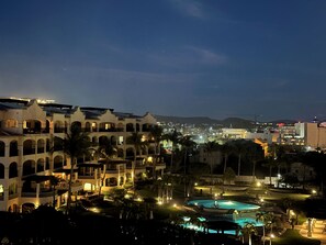 A resort with multiple buildings, a swimming pool, and palm trees.
