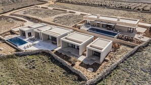 Une villa moderne à plusieurs étages, dotée d’une piscine, d’un espace salon extérieur et offrant une vue sur le paysage environnant.