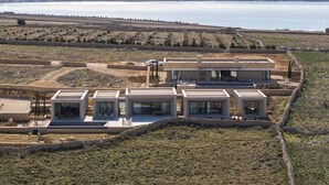 Une villa moderne composée de plusieurs unités communicantes, dotée d’un vaste espace extérieur et offrant une vue sur un lac.