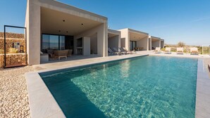 A modern poolside area with clear blue water, a stone wall, and lounge chairs. - Villa Salina with Pool (Povljana)