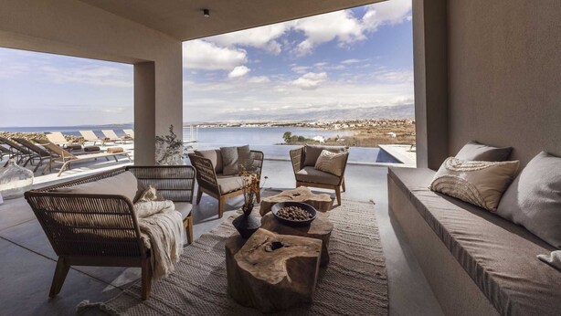 A spacious balcony with a view of the sea and a distant town. There are wicker chairs, a sofa, and a coffee table with a bowl of nuts. - Villa Salina with Pool (Povljana)