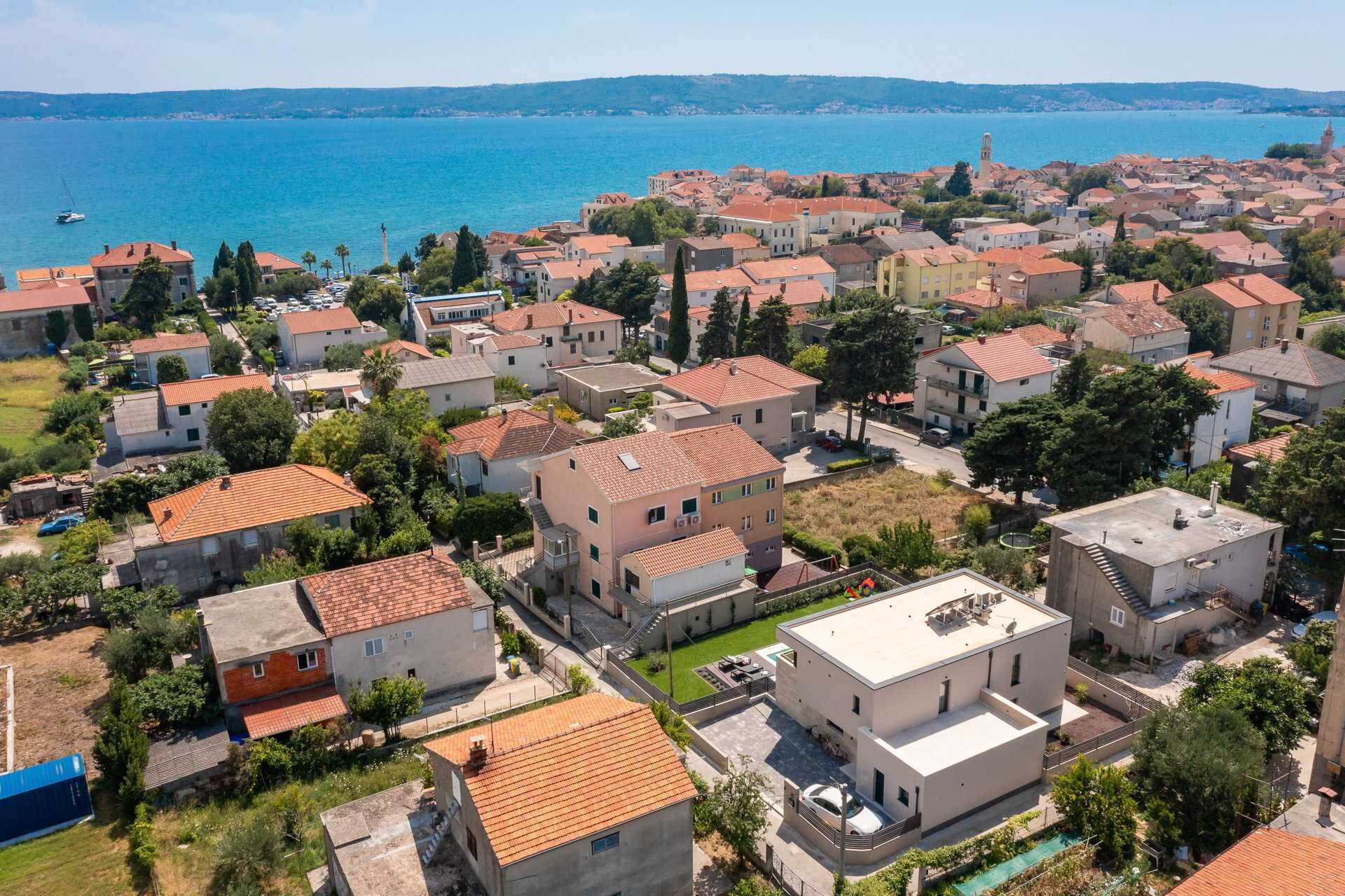 A coastal residential area with houses featuring red-tiled roofs and a mix of modern and traditional architecture.