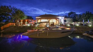 A boat docked at a waterfront property with a house and outdoor seating area. - Villa Aquaterra with pool (Nin)