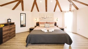 A bedroom with a large bed, wooden beams, a painting, a nightstand, a dresser, and a mirror. - Villa Aquaterra with pool (Nin)