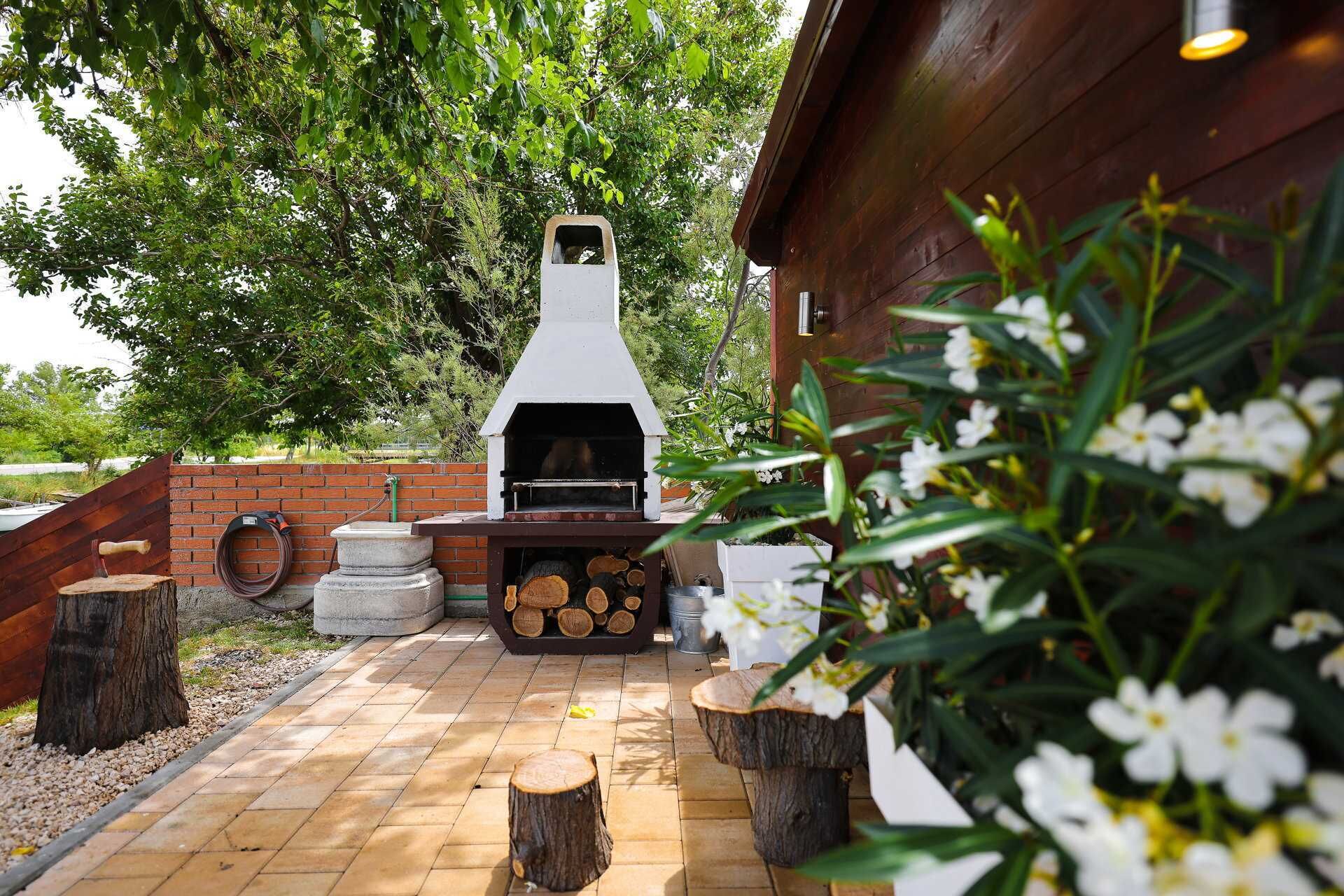 An outdoor barbecue area with a chimney, firewood, and a brick wall.