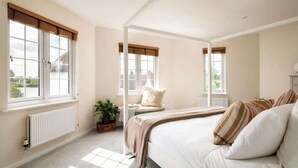 A bedroom with a large bed, a window seat, and a radiator.