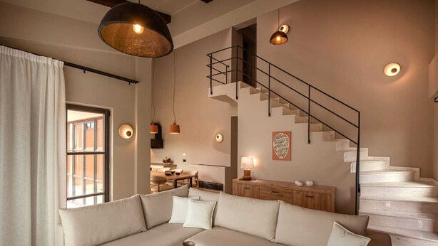 Ein modernes Wohnzimmer mit einem beigen Sofa, einem Holztisch und einer Treppe mit schwarzer Geländer.