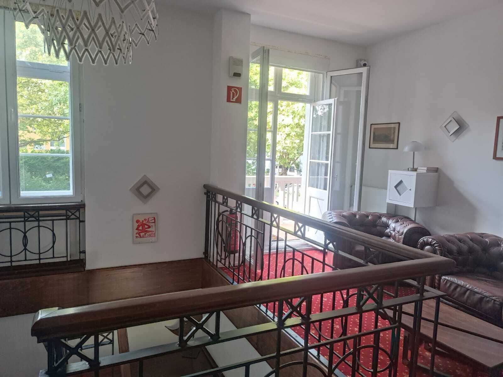 A room with a staircase, a red carpet, a leather sofa, and a white lamp.