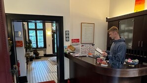Un espace d’accueil comprenant un comptoir d’enregistrement, un tapis rouge et un sol carrelé.