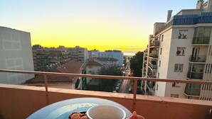 A balcony with a table, a cup, and a plate of pastries.