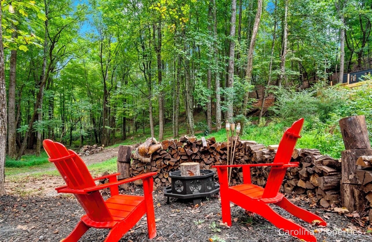 Waldszene mit Lagerfeuer und zwei roten Adirondack-Stühlen.