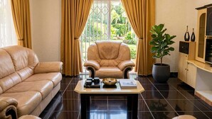 A living room with a leather sofa, a matching armchair, a coffee table with decorative items, and a potted plant.