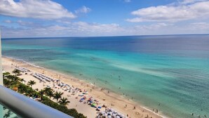 A beach with clear turquoise water, a sandy shore, and umbrellas. - The Tides (Hollywood)
