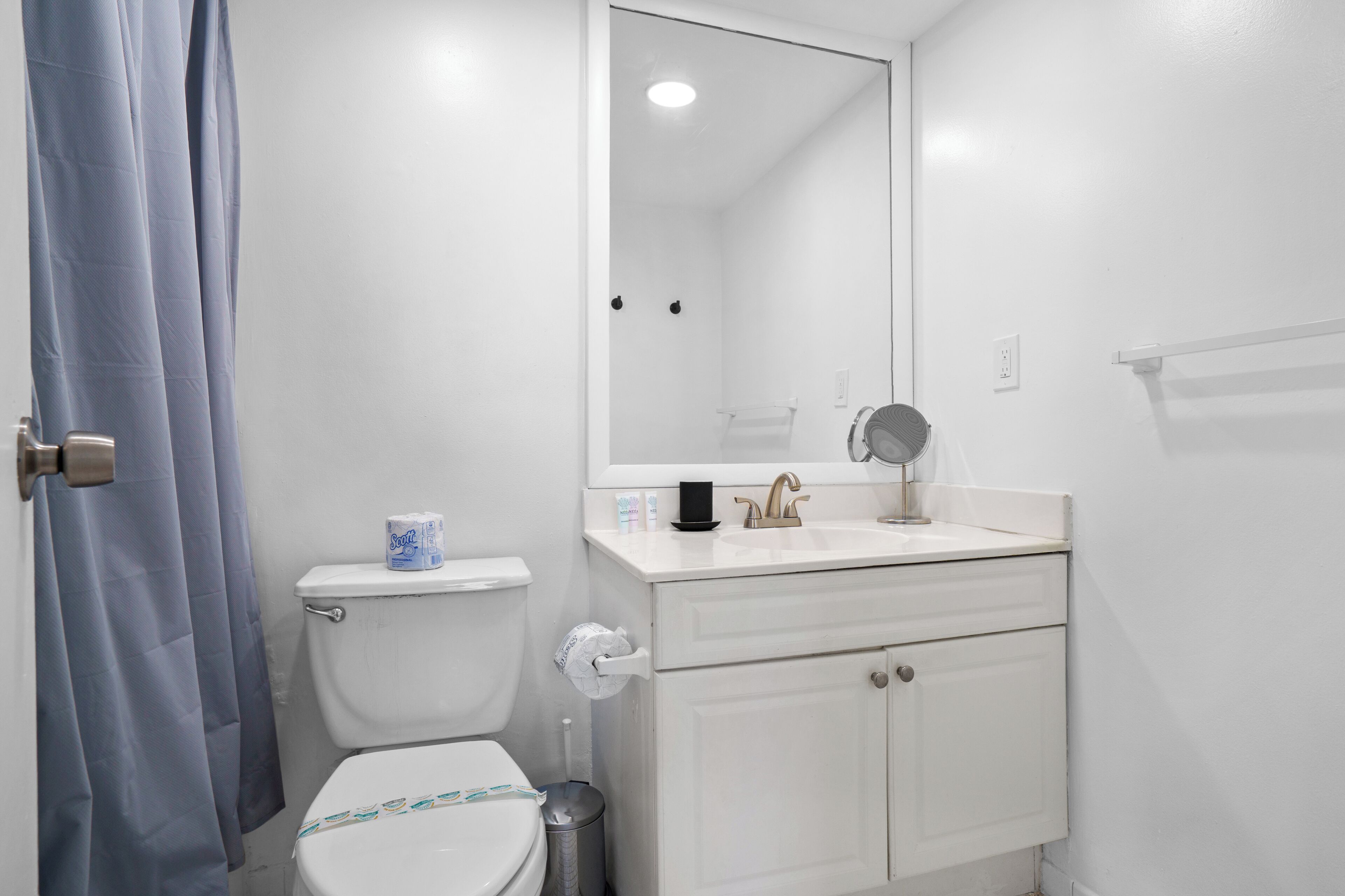 Une salle de bain équipée de toilettes, d’un lavabo, d’un miroir et d’une poubelle.