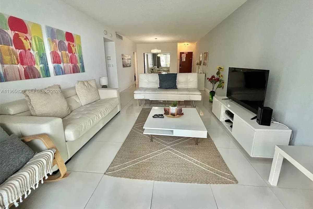 Una sala moderna con sofá, mesa de centro, televisor y un cuadro abstracto colorido en la pared.