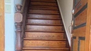 A wooden staircase with a handrail, leading to a door with a glass panel.
