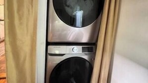 A compact laundry room with two stacked washing machines and a dryer.