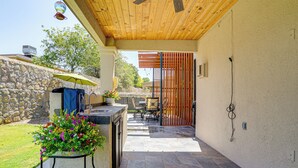 Un patio cubierto con un muro de piedra, muebles de exterior y una planta en maceta.