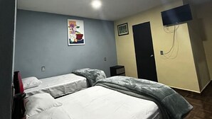 Une chambre avec deux lits, un téléviseur fixé au mur et une porte.