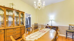 Comedor con una mesa de madera, sillas, una araña y un aparador con puertas de cristal.