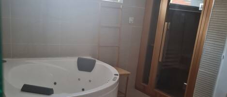 Un baño con bañera, ducha y tragaluz.