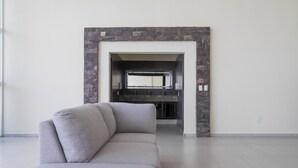 A modern living room with a grey sofa, a stone fireplace, and a tiled floor. - House with Terrace & Pool in Coyula (Tonala)