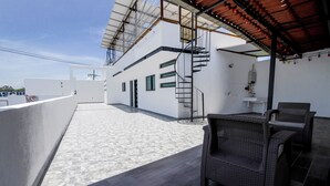A rooftop terrace with a covered seating area, a spiral staircase, and a view of the city skyline. - House with Terrace & Pool in Coyula (Tonala)