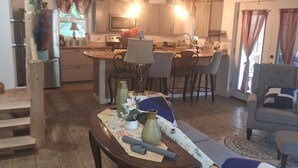 Un amplio salón con una mesa de comedor, un sofá y una cocina al fondo.