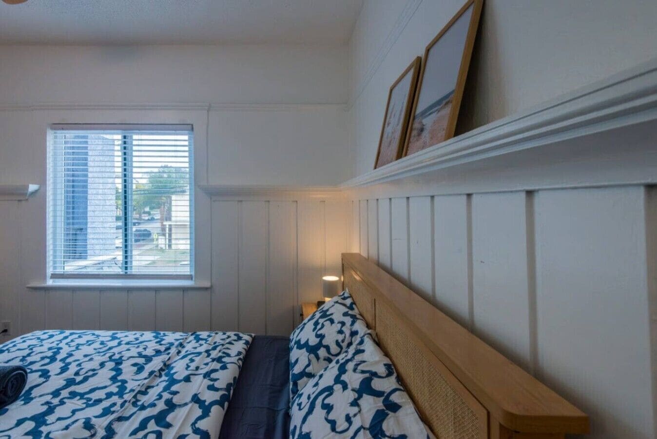 A bedroom with a bed, a window, and a wall-mounted shelf.