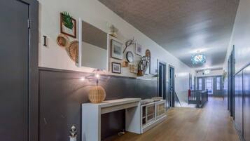 A hallway with a white console table, a decorative lamp, and wall-mounted decor.