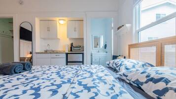 A bedroom with a bed, a small kitchenette, and a bathroom.