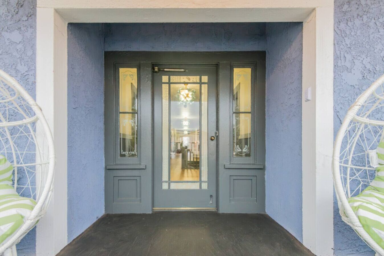 Una puerta doble gris con paneles de vidrio y un candelabro en el interior.