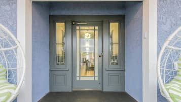A grey double door with glass panels and a chandelier inside.