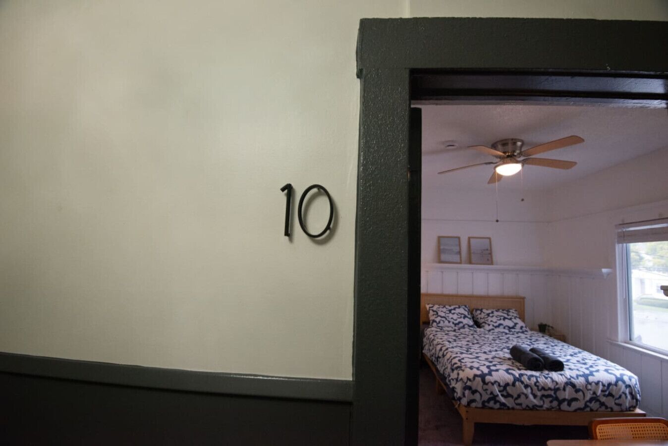 Una stanza con un letto, un ventilatore a soffitto e una finestra.