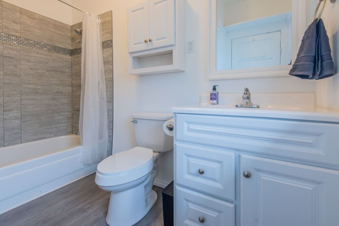 Un baño con ducha, inodoro y tocador con cajones.