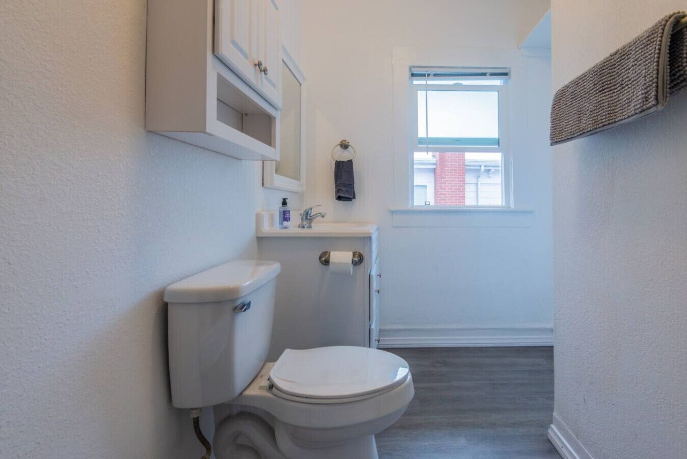 Une petite salle de bain comprenant des toilettes, un lavabo et une fenêtre.