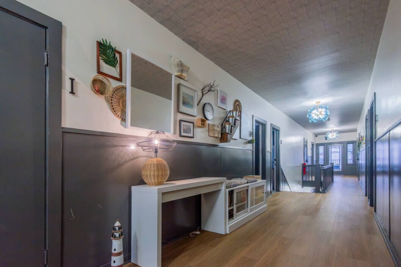 Una cocina moderna con encimera blanca, lámpara colgante y escalera que sube a otro nivel.