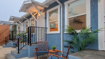 A residential building with a blue exterior, white trim, and a covered porch with outdoor furniture.