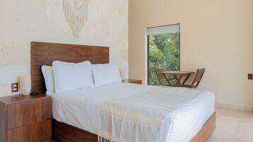 A bedroom with a wooden bed, a nightstand, a chair, and a window with a view of greenery.