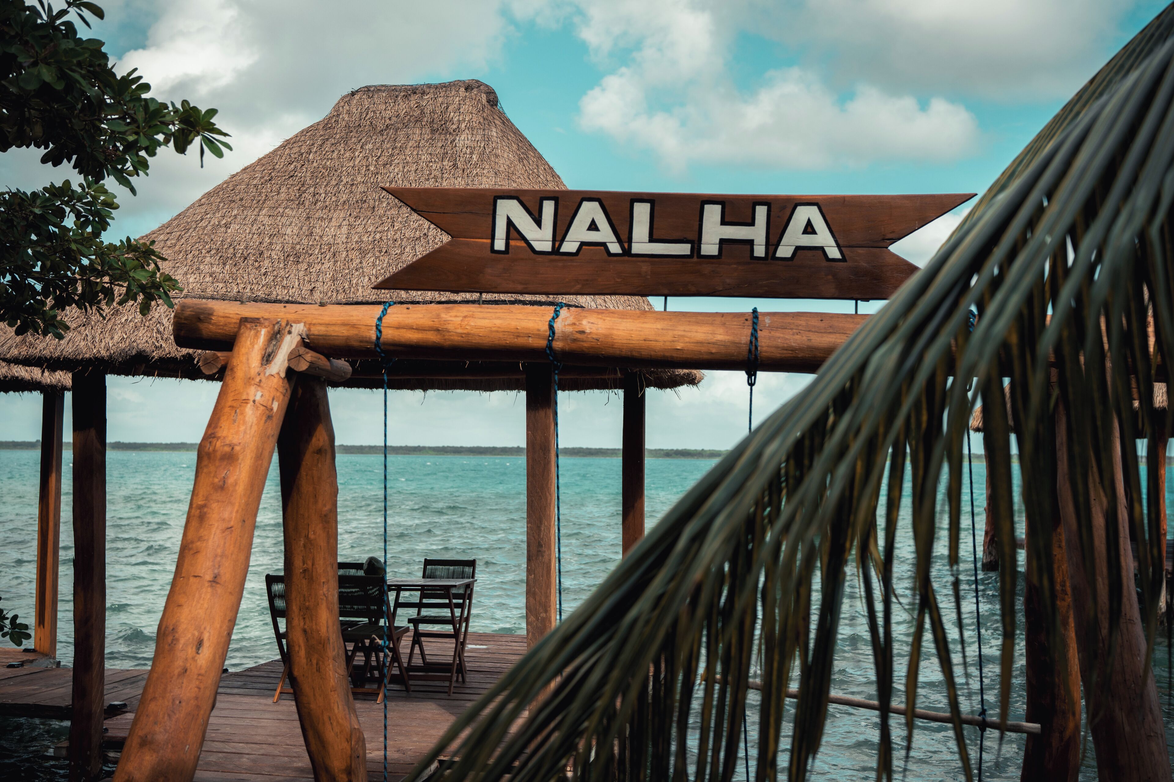 Una estructura de madera con un cartel que dice 'NALHA' y vista al mar.