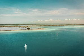 A coastal landscape with clear turquoise waters, a sandy beach, and a small sailboat. - Nalhá Hotel Boutique y Villas Bacalar (Bacalar)