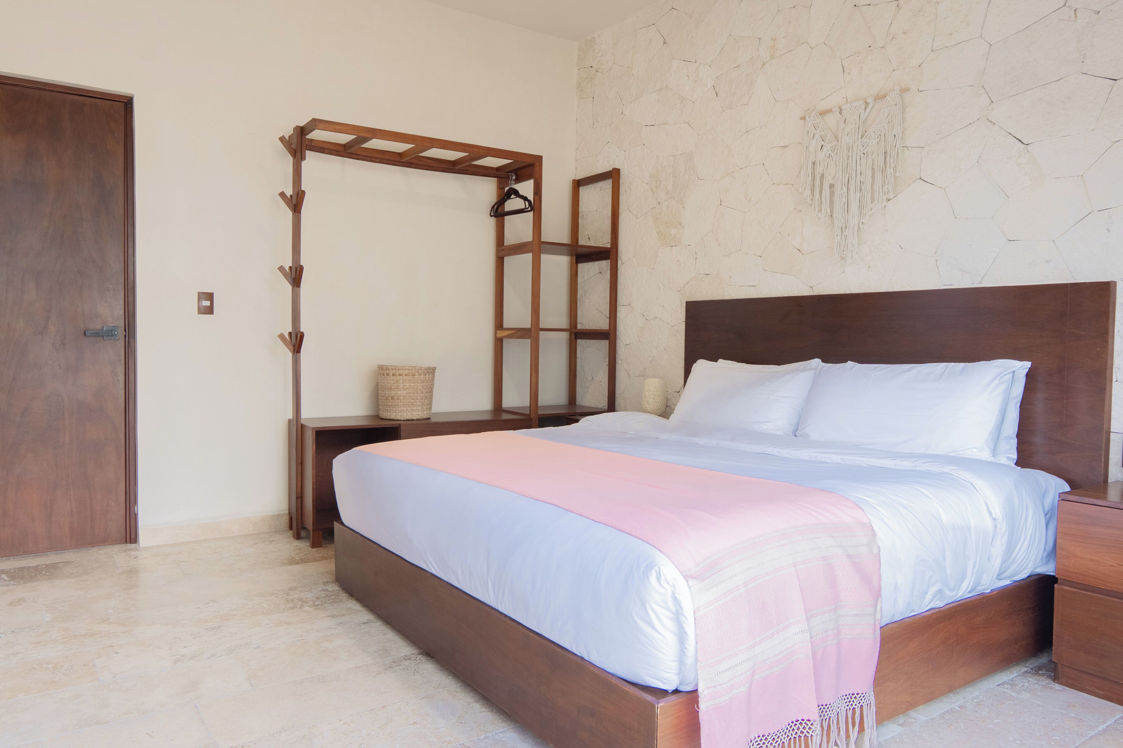 Un dormitorio con una cama de madera, una mesita de noche, un armario de madera y un estante en la pared.