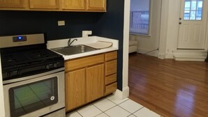 Une cuisine avec des meubles de rangement en bois, un évier en acier inoxydable, une cuisinière et un four.