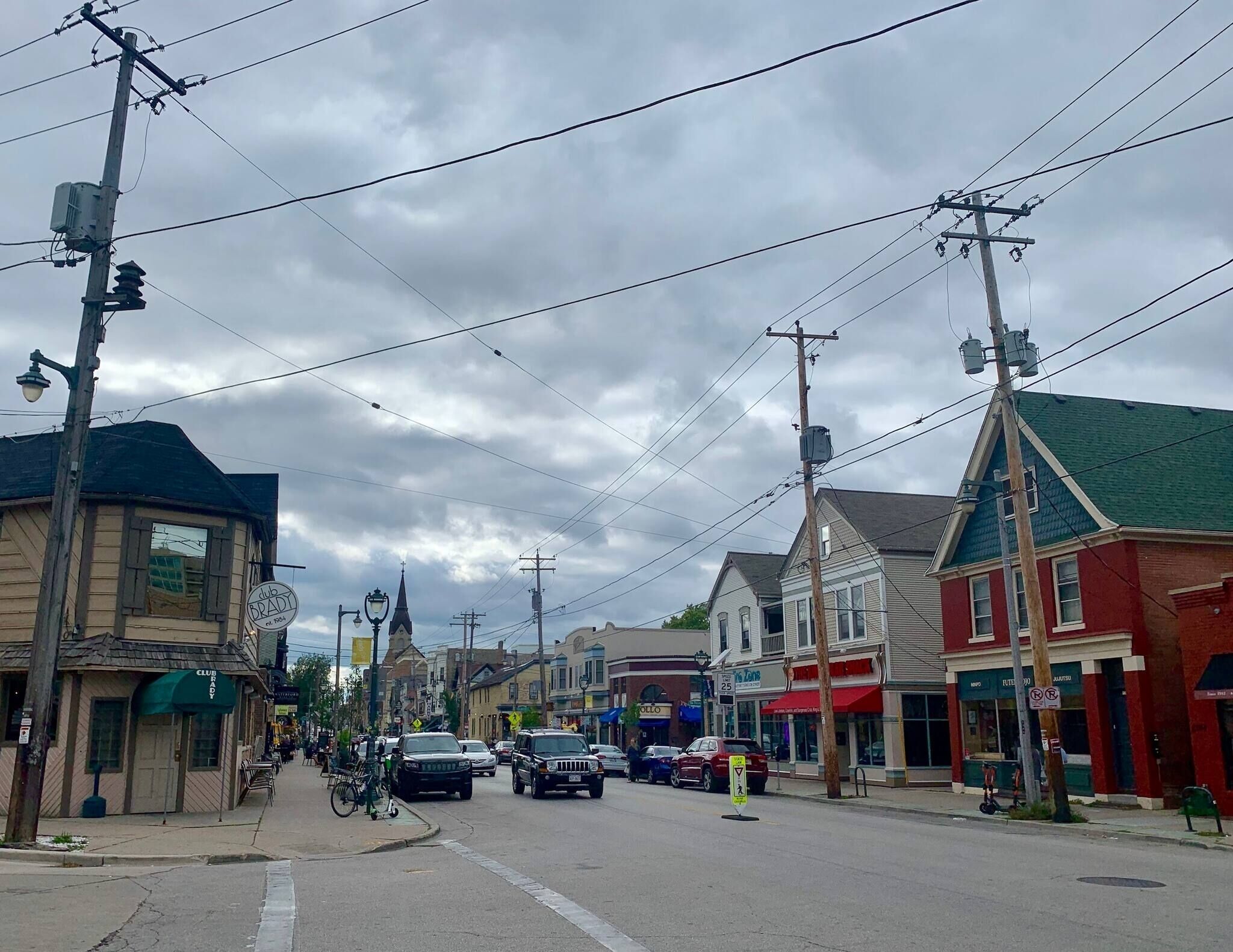 A street lined with buildings, including a Club Brady and a 25 store.