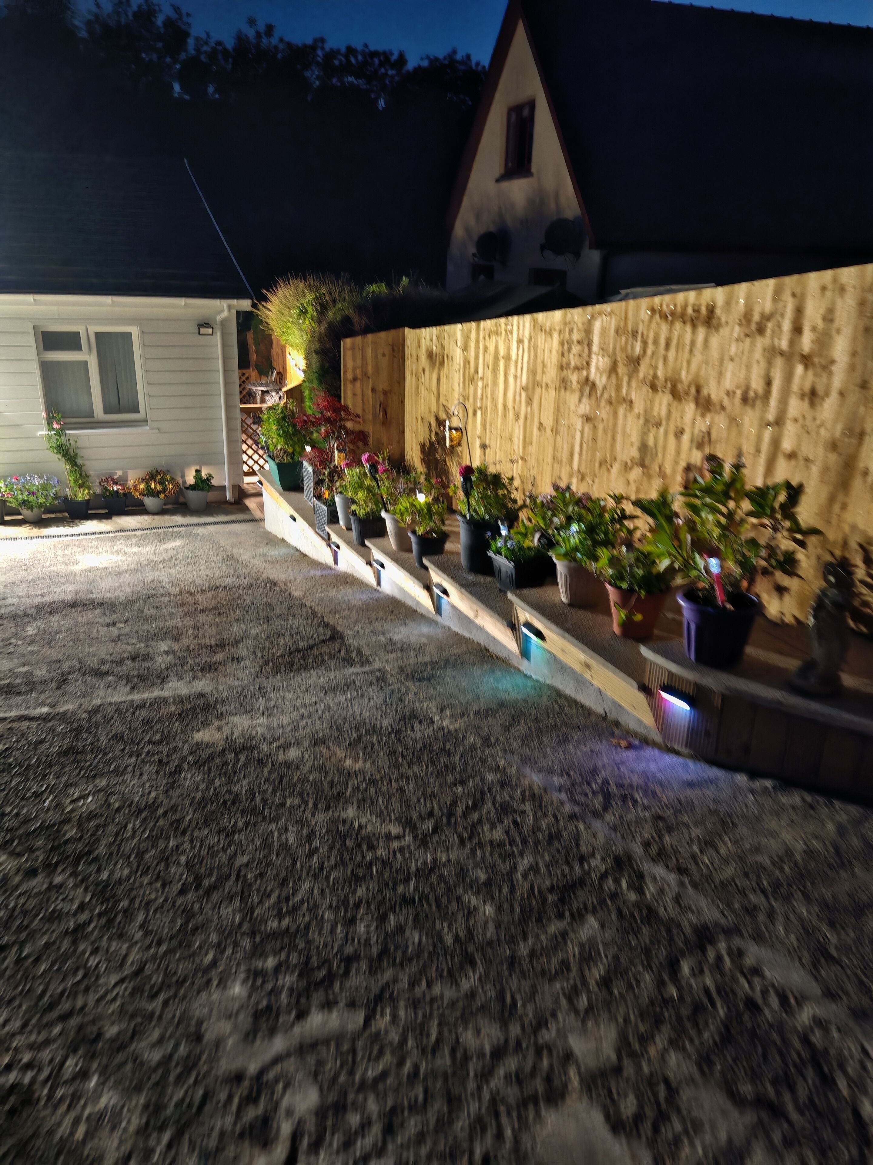 Ein Haus mit einer Holzwand und einer Veranda mit Blumentöpfen.