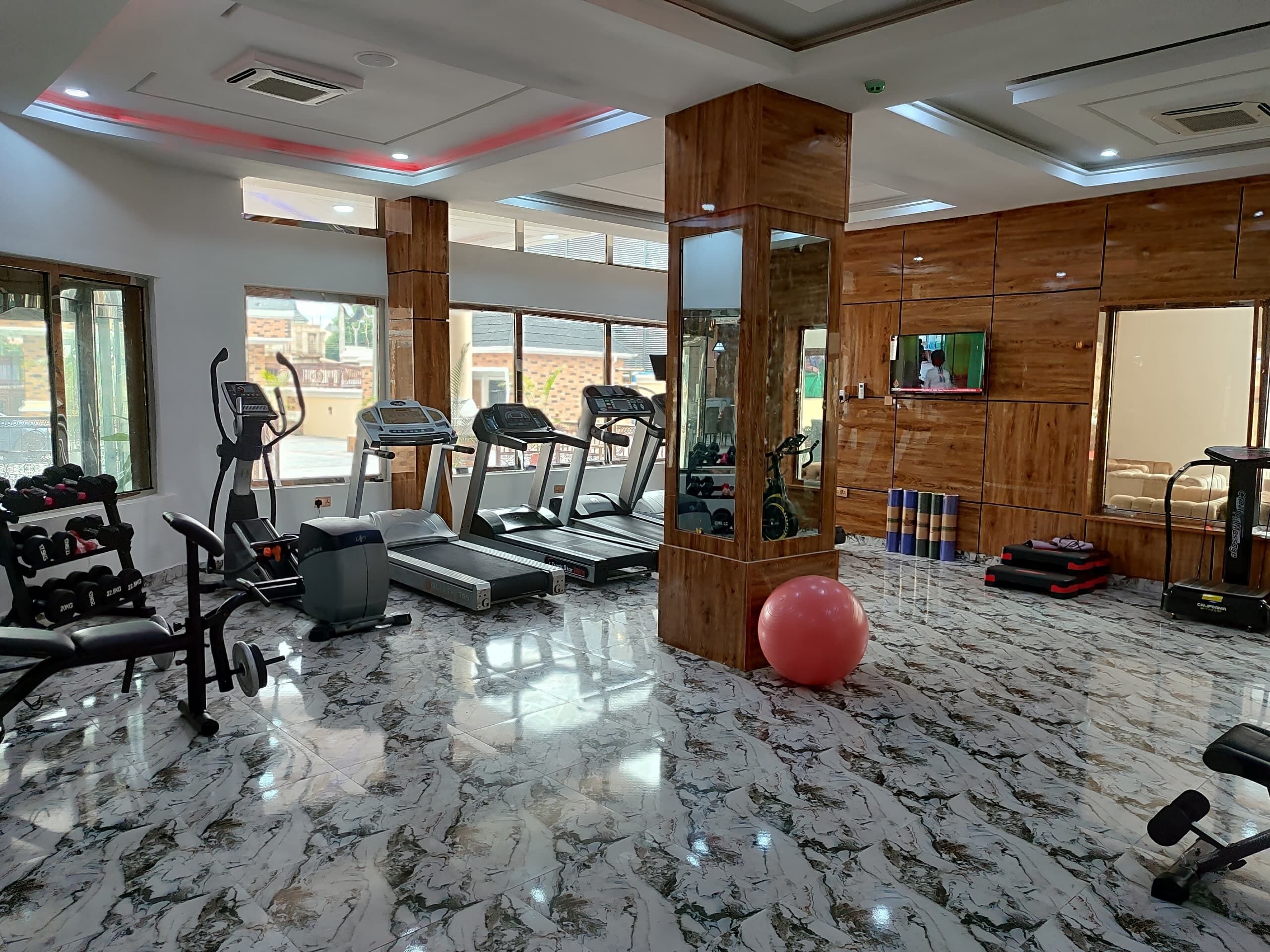 A gym with treadmills, dumbbells, and exercise balls.